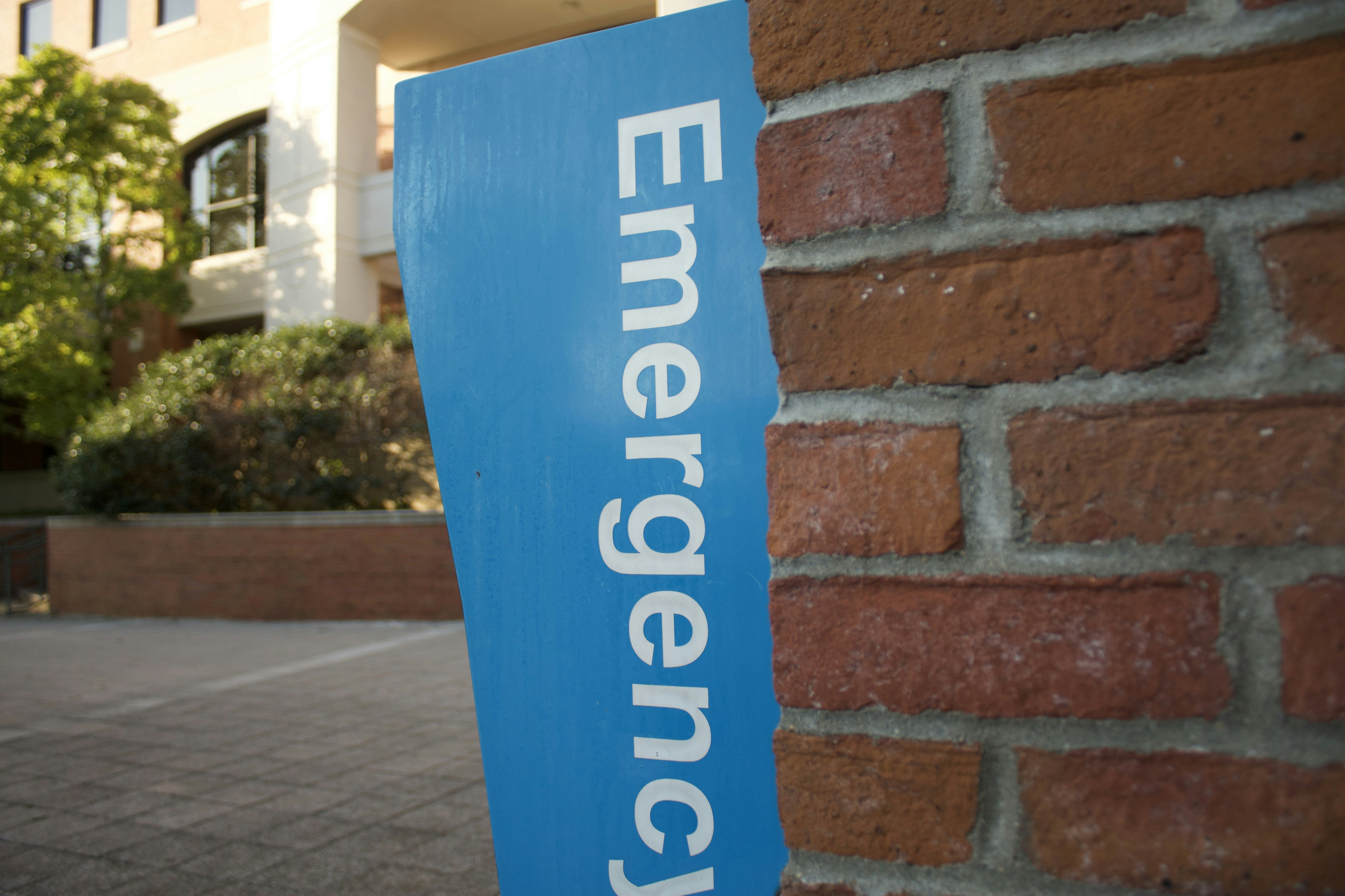 a blue emergency sign on a brick wall