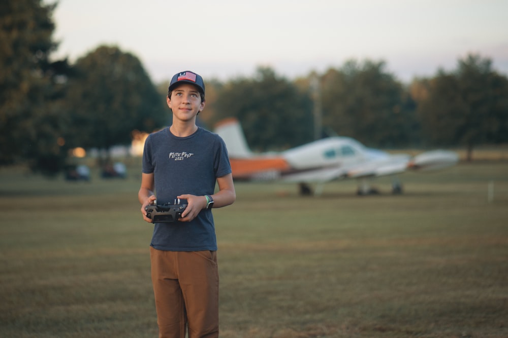 a young man standing in a field holding a camera