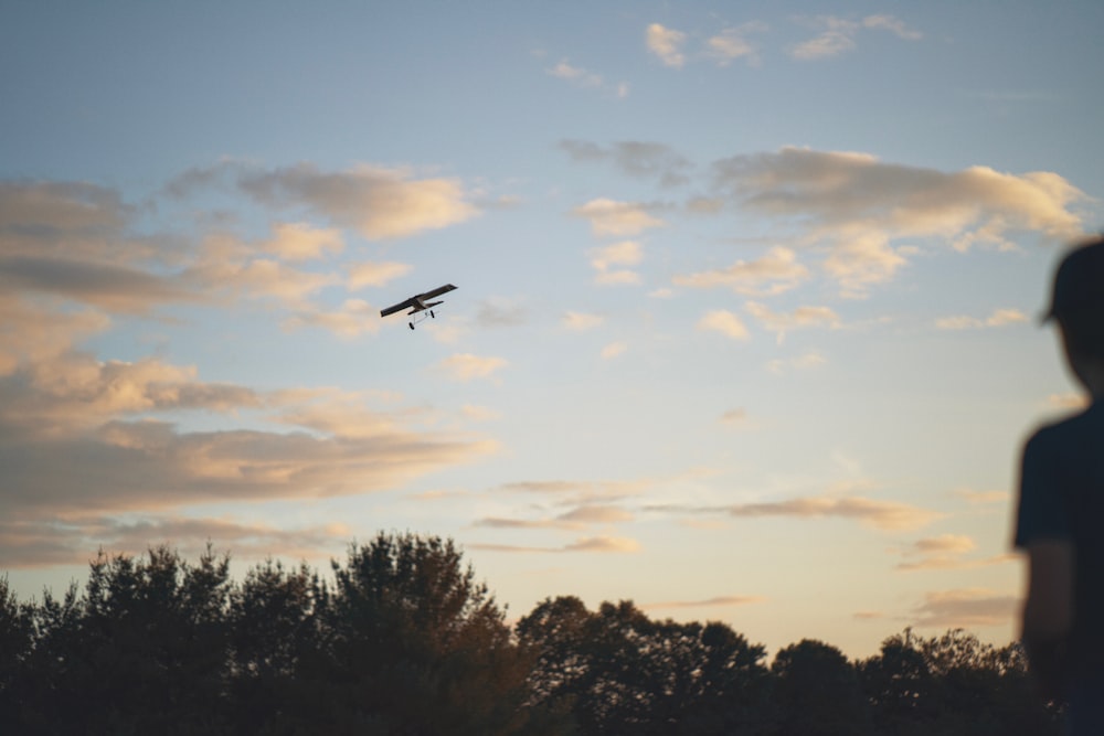 a person looking at a plane flying in the sky