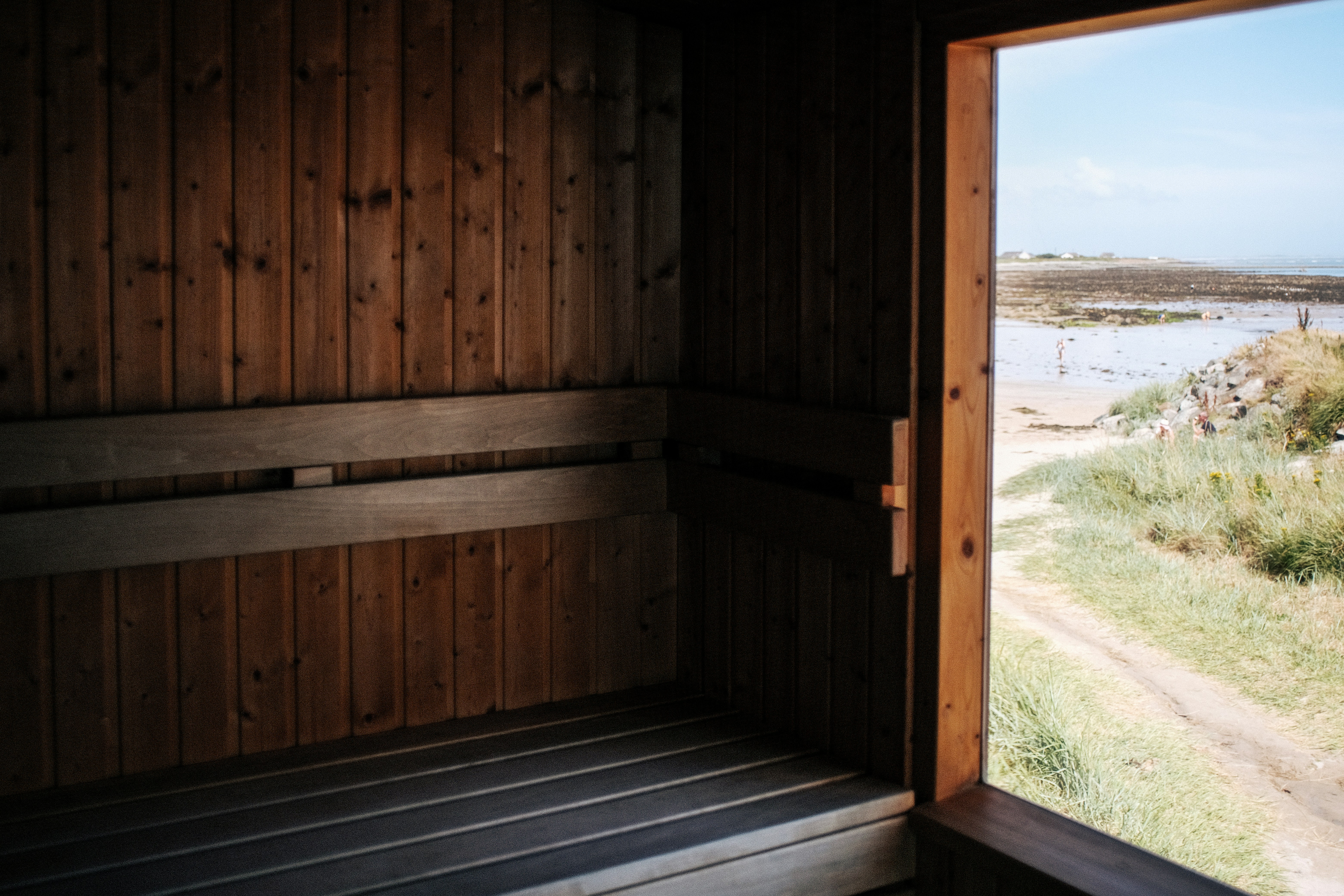 a wooden sauna with a view of a beach