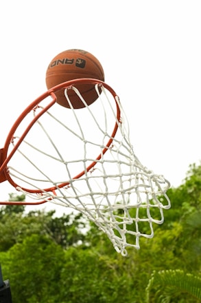 Close-up of a basketball hoop with a ball about to go through the net.