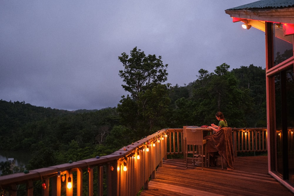 a woman sitting at a table on top of a wooden deck