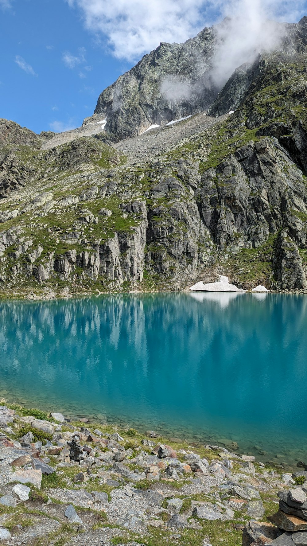 a blue lake surrounded by rocky mountains under a cloudy sky