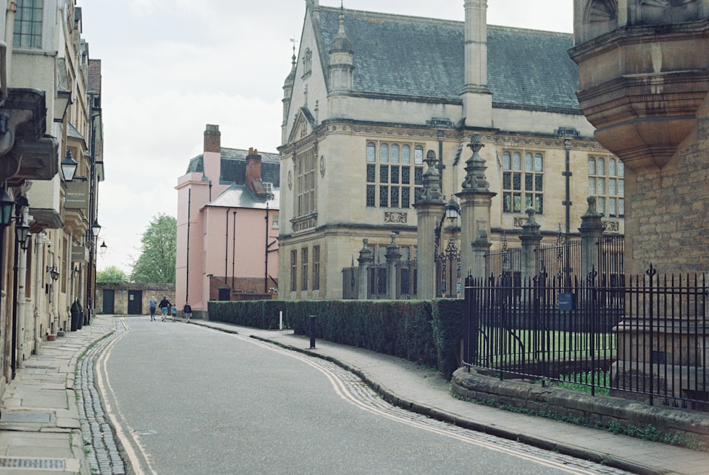 a street lined with tall buildings next to a fence