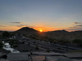A serene desert landscape at sunset with a winding road leading into Death Valley.