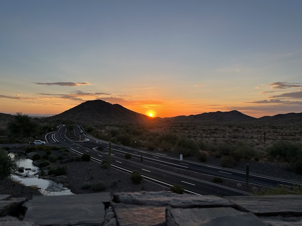 A scenic view of the Oman desert road at sunset, highlighting the journey between cities.