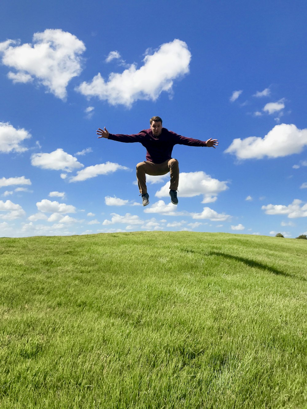 a man is jumping in the air on a grassy hill
