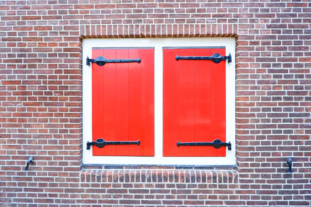 a red brick wall with two windows and bars