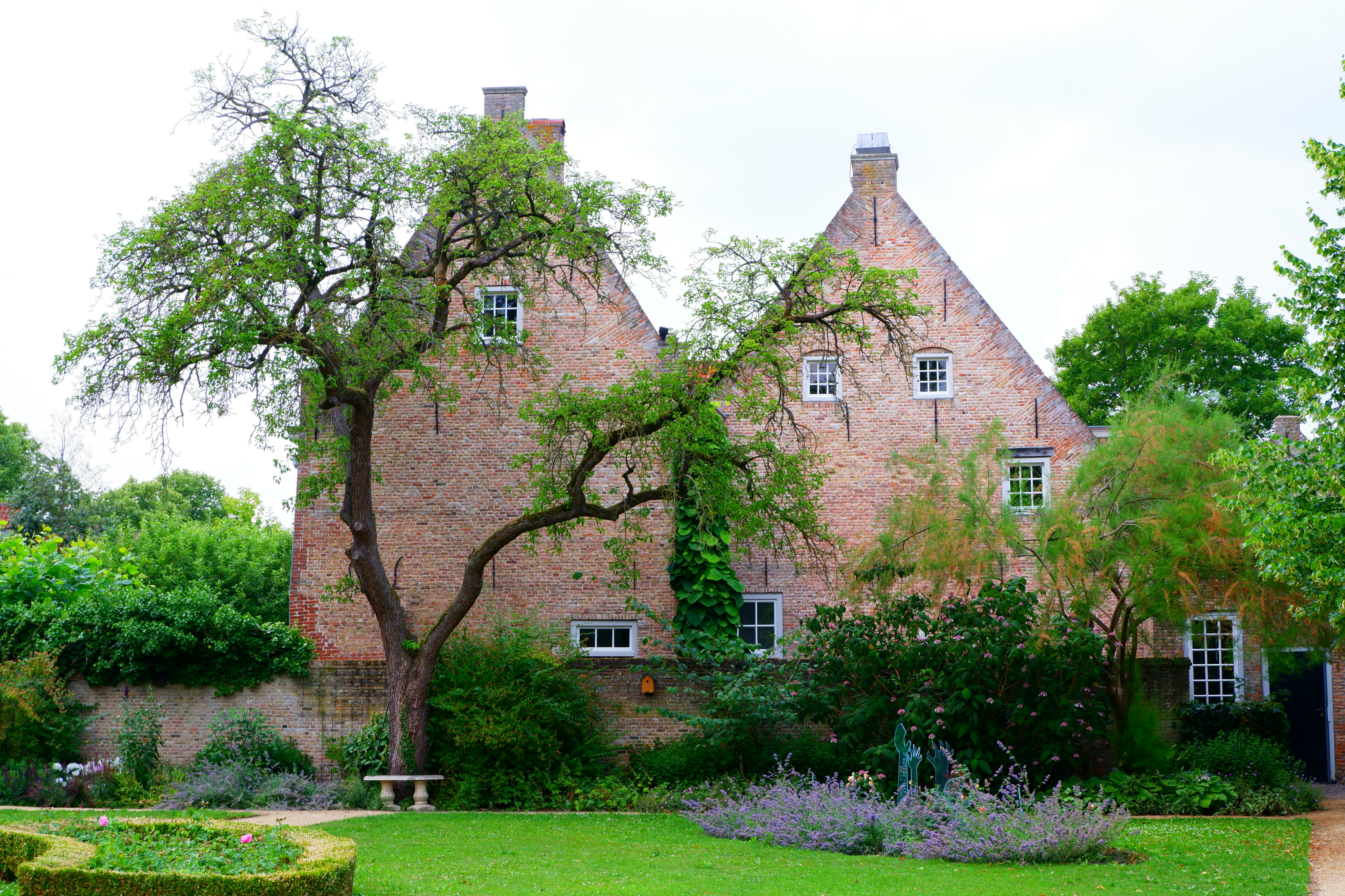 a large brick house with a garden in front of it, 