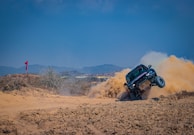 4x4 vehicle kicking up red dust on a rugged track through the rocky Agafay Desert.