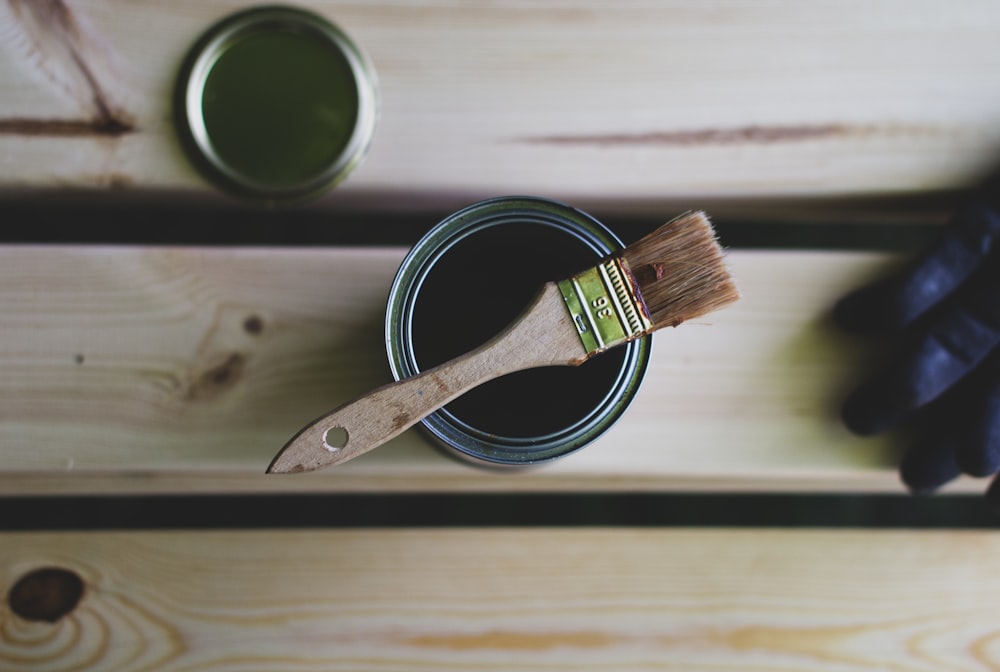 a paint can with a brush on top of it