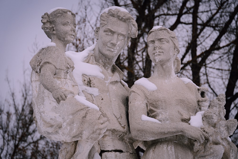 Una estatua de tres personas de pie una al lado de la otra