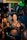 A lively party scene with individuals gathered closely together. People are holding smartphones and drinks, capturing moments and engaging with each other. The environment is vibrant with a dimly lit, colorful background and a dense crowd.
