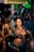 A lively party scene with individuals gathered closely together. People are holding smartphones and drinks, capturing moments and engaging with each other. The environment is vibrant with a dimly lit, colorful background and a dense crowd.