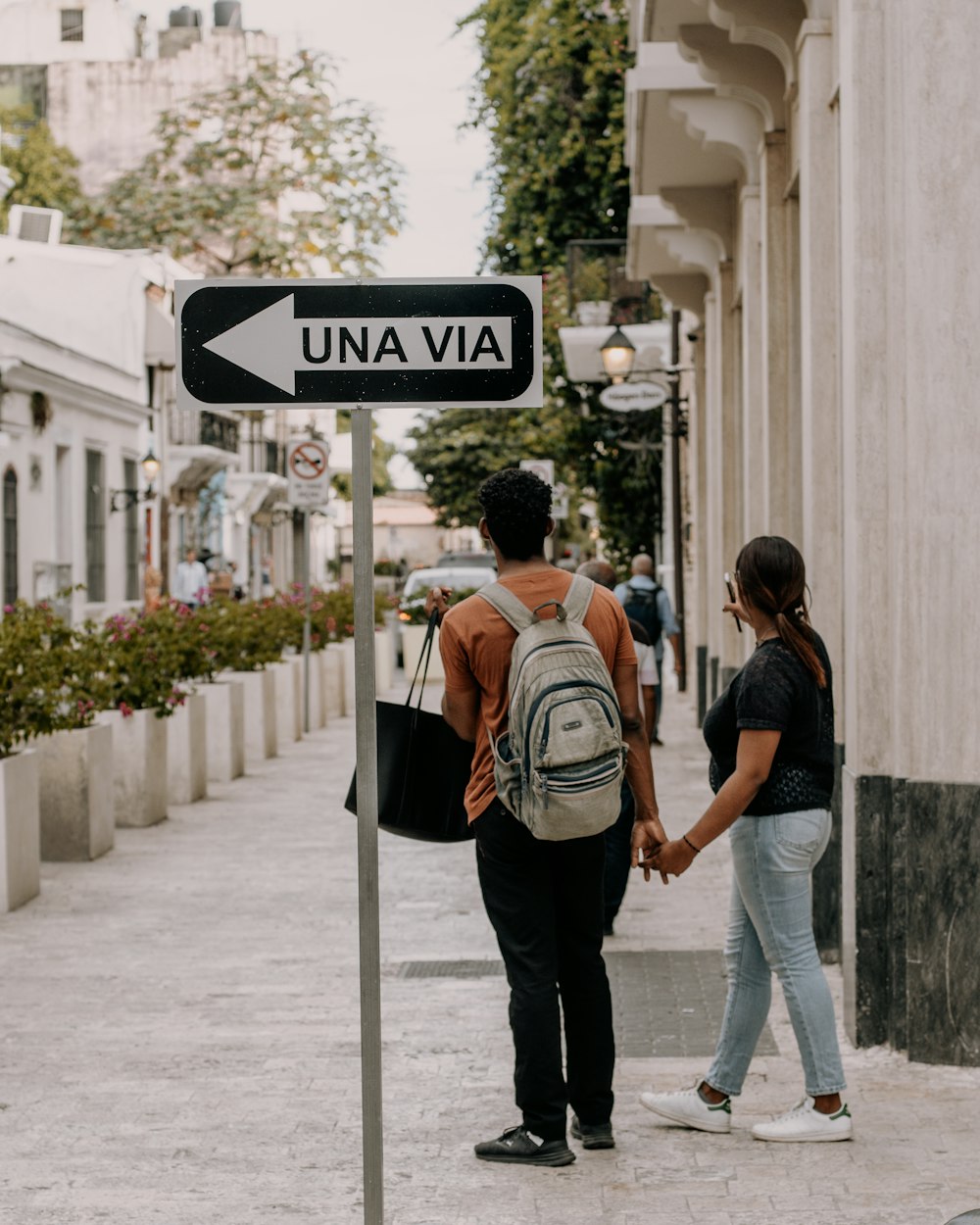 a couple of people walking down a street holding hands