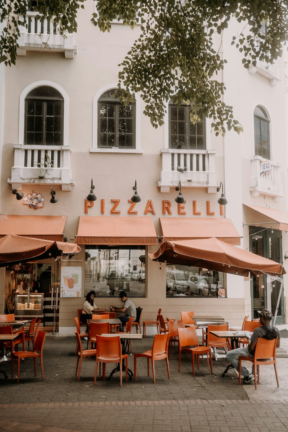 a couple of people sitting at a table outside of a restaurant