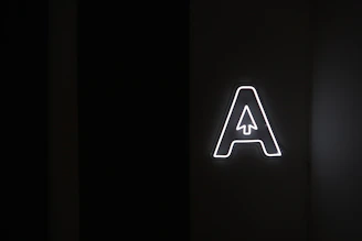 A minimalist black background with glowing cyan circuit lines forming a stylized 'A' symbol.