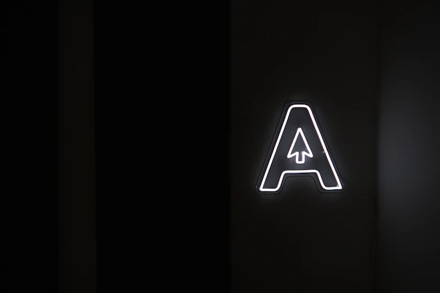 A minimalist black background with glowing cyan circuit lines forming a stylized 'A' symbol.