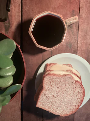 Warm coffee cup on a wooden table next to freshly baked focaccia.