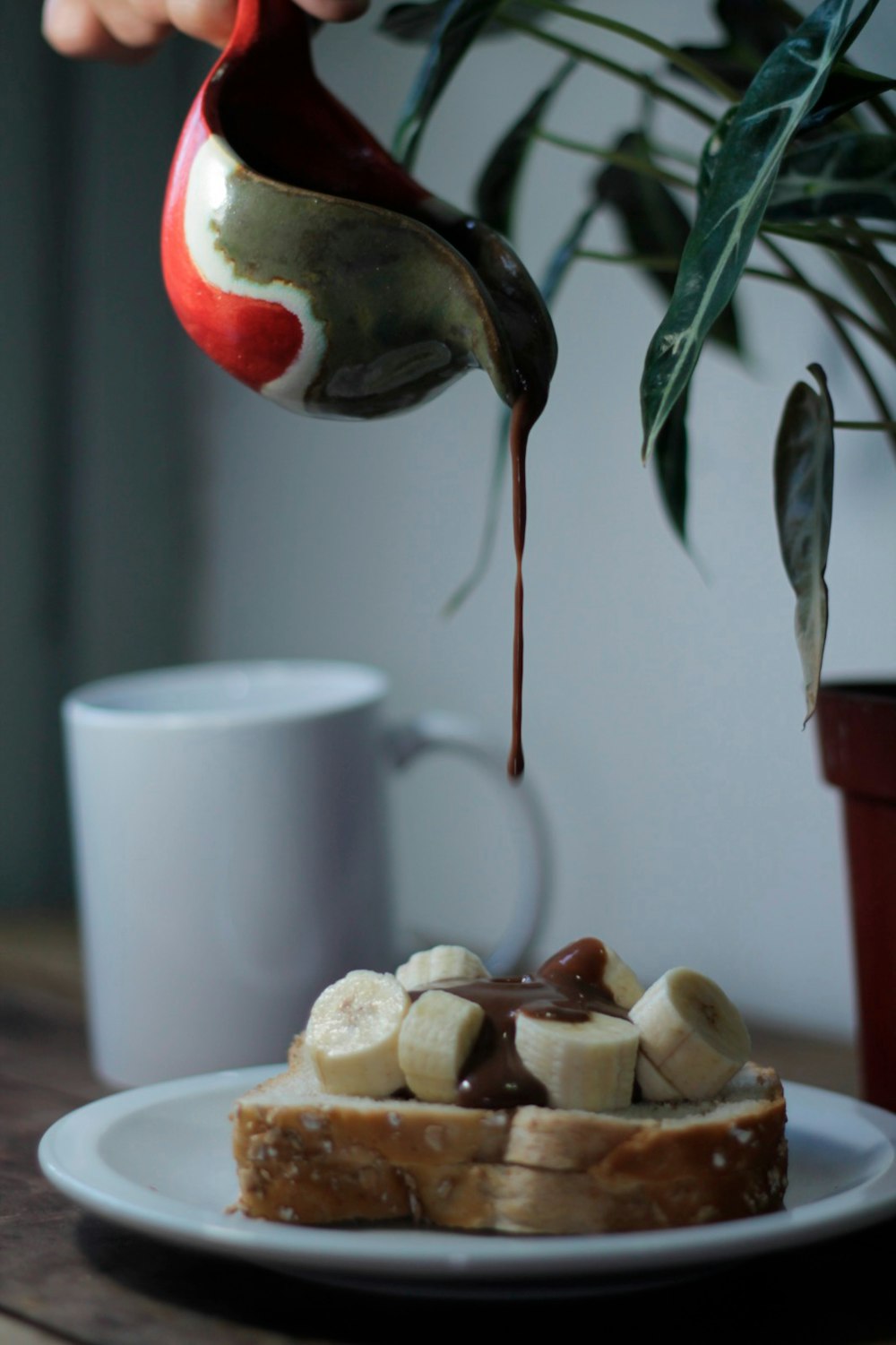 a person pouring chocolate onto a piece of bread