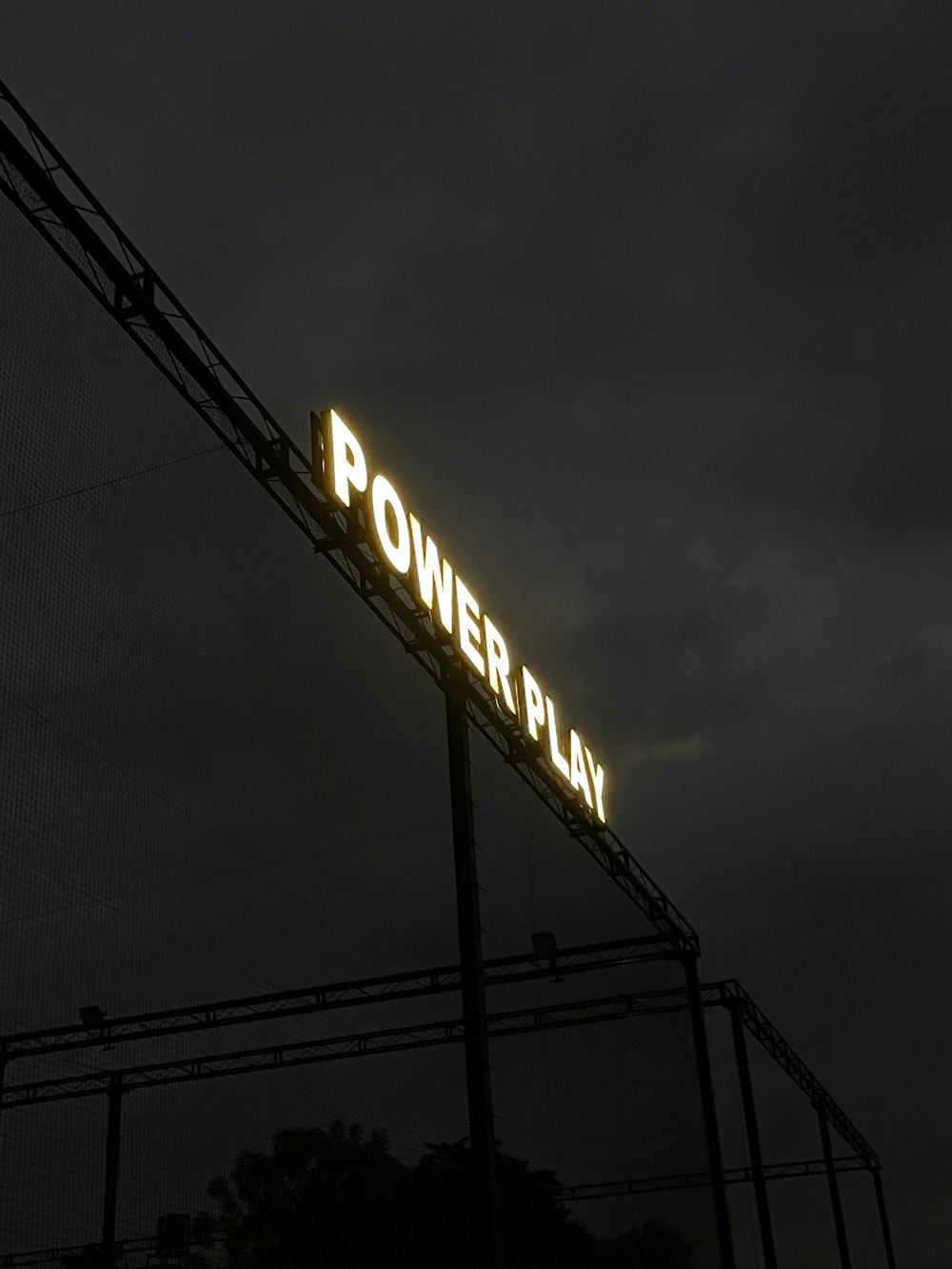 a power play sign lit up against a dark sky