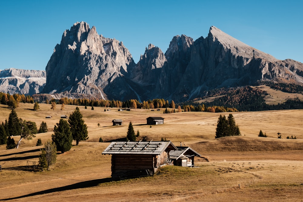 a small cabin in a field with mountains in the background