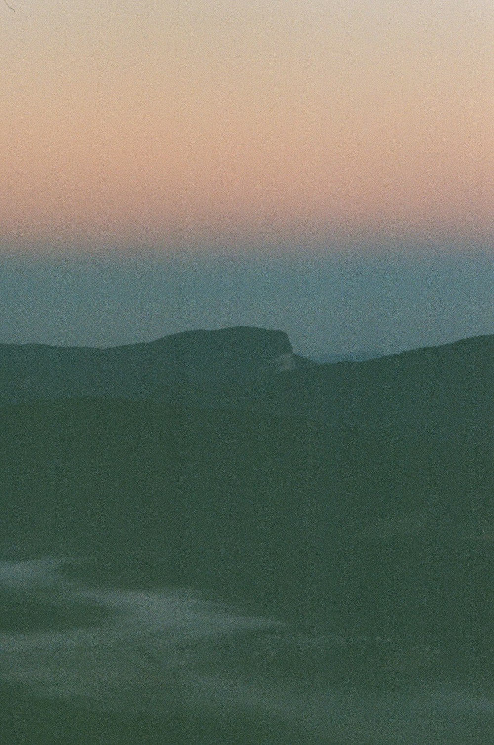 a plane flying over a mountain range at sunset