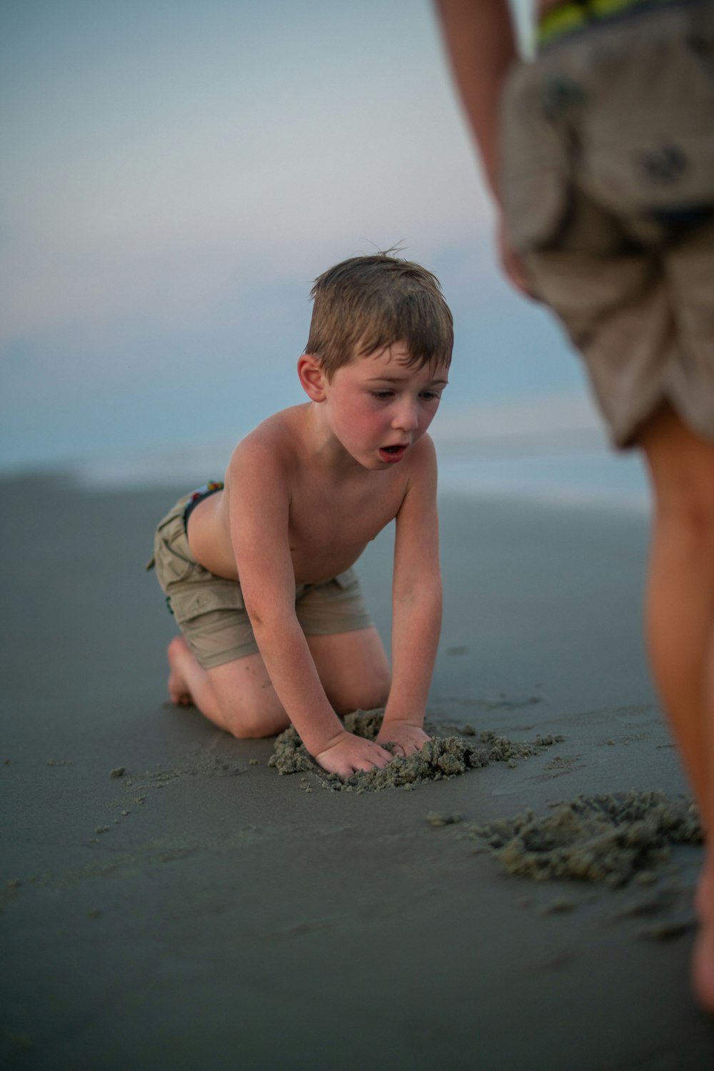 a young boy playing in the sand on the beach