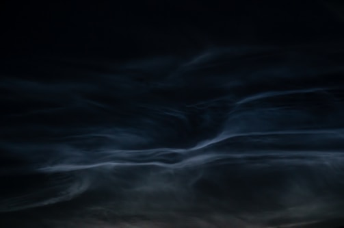 A mysterious mage casting a swirling water spell under dark clouds.