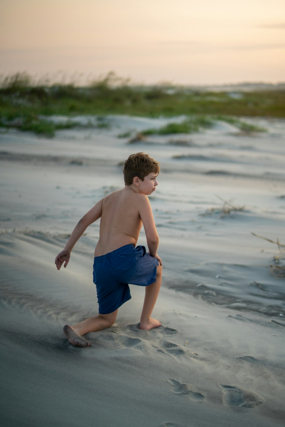 어린 소년이 해변의 모래에서 놀고 있다