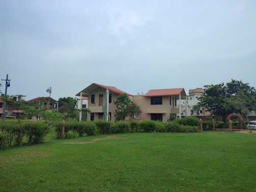 a large grassy field with houses in the background