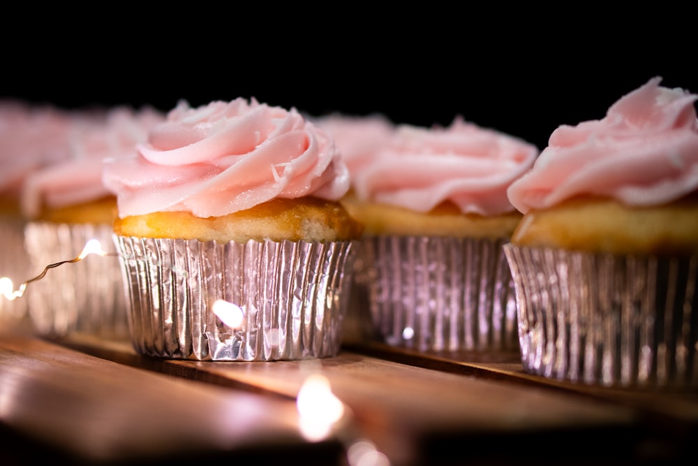 cupcakes with pink frosting sitting on a table