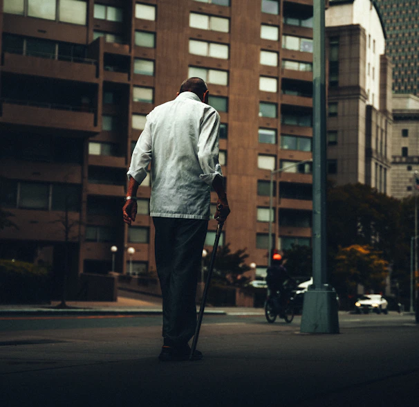 Close-up of a pair of hands adjusting a mobility cane on a city sidewalk.