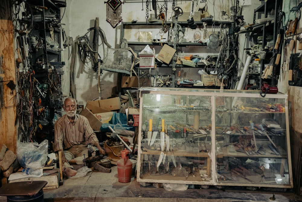 a man sitting in a room filled with lots of clutter