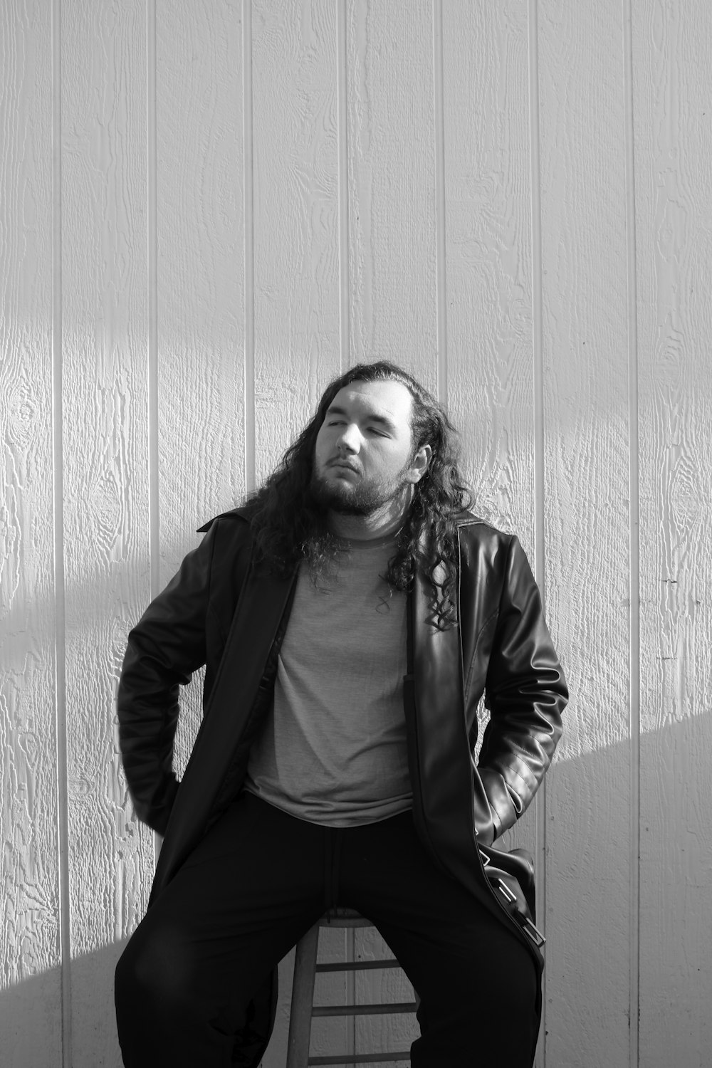 a man with long hair sitting on a bench