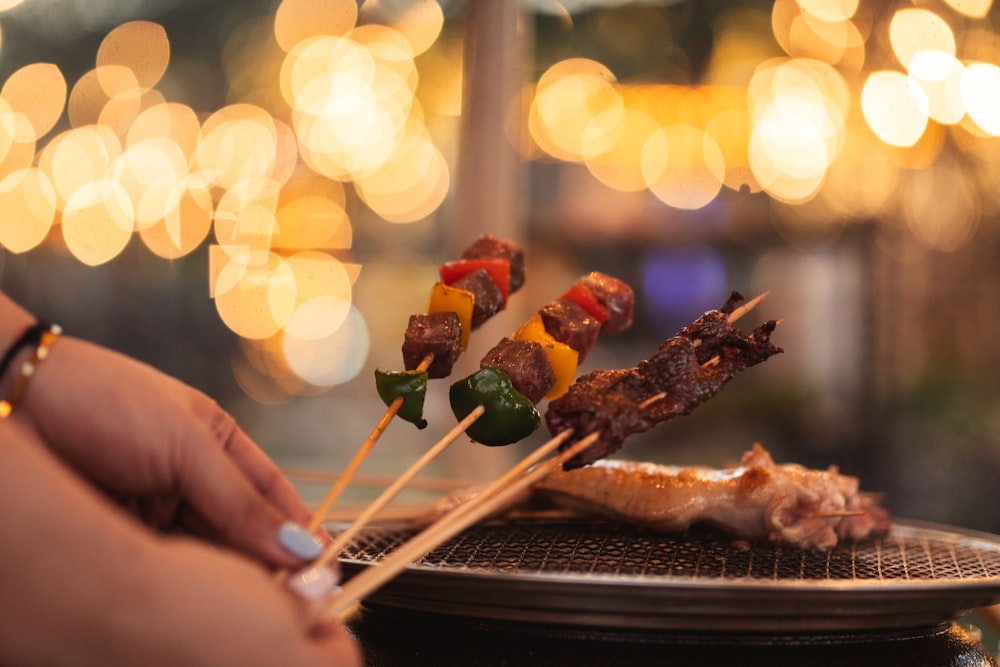 a person holding a skewer of food on a grill