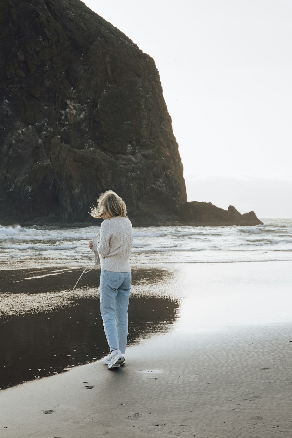 a woman standing on top of a beach next to the ocean