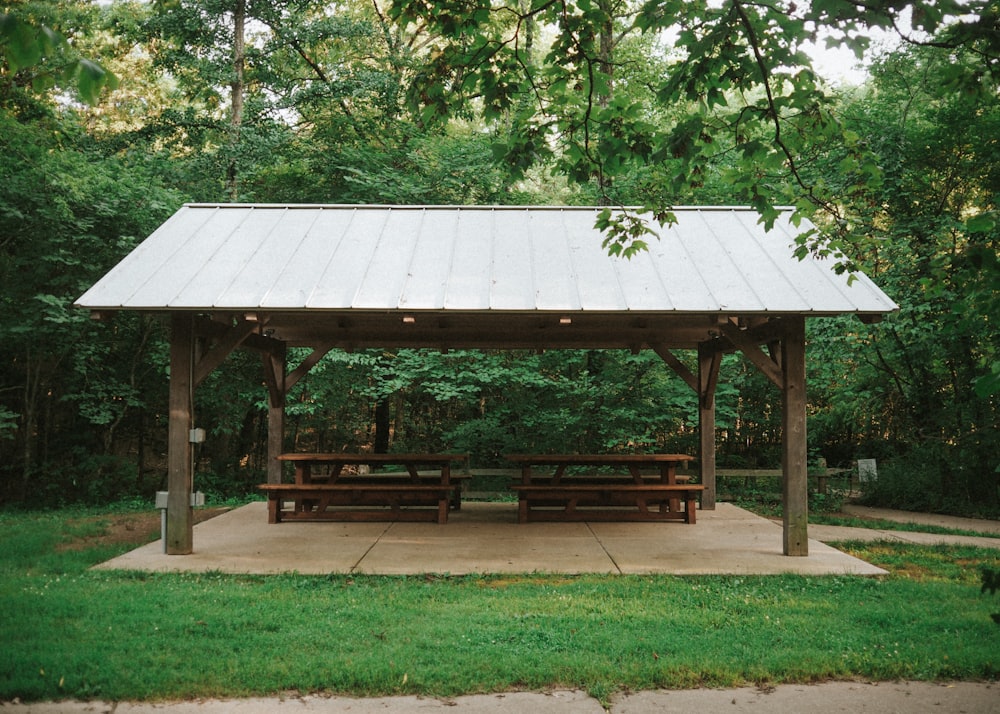 a covered picnic area in a park with picnic tables