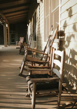 A cozy farmhouse porch with hanging herbs and a wooden rocking chair bathed in warm sunlight.
