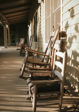 Wide shot of a sunny porch with rocking chairs and a built-in outdoor grill.