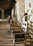 A warm, rustic wooden porch with a rocking chair and a sunset over a horse farm.