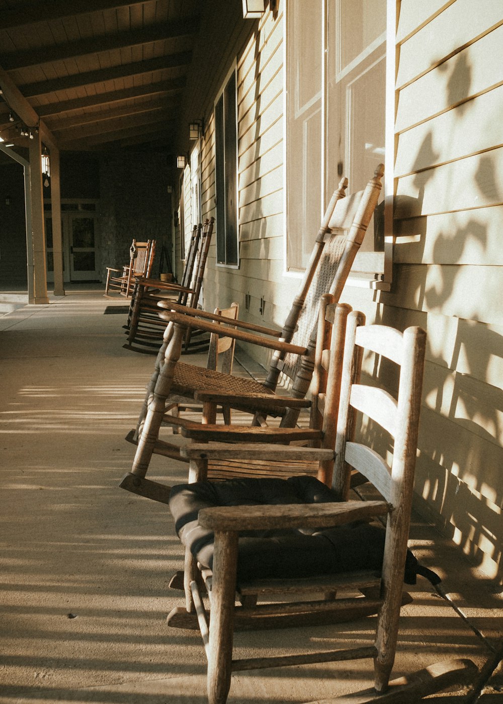 a row of wooden rocking chairs sitting on a porch