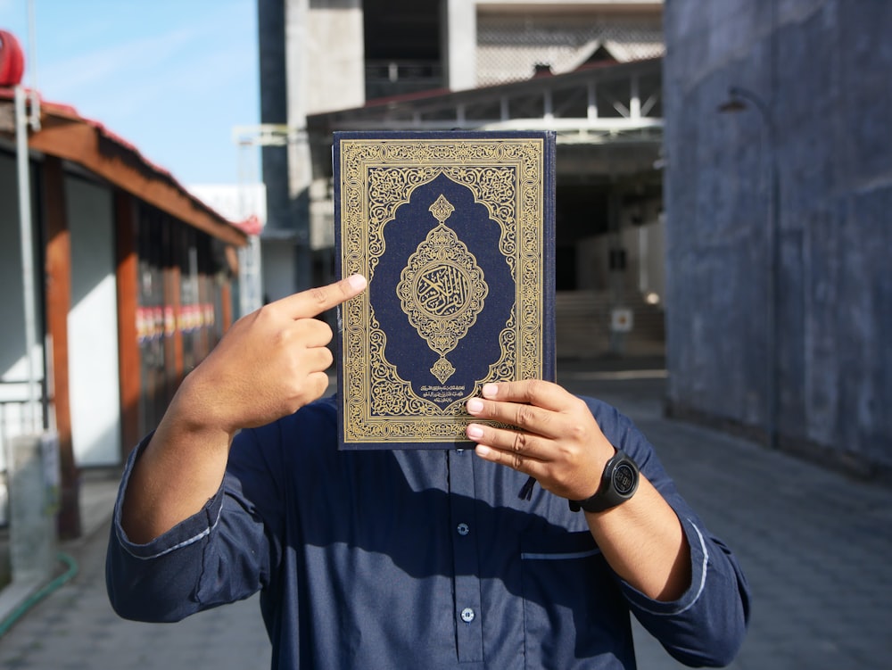 a man holding up a book in front of his face