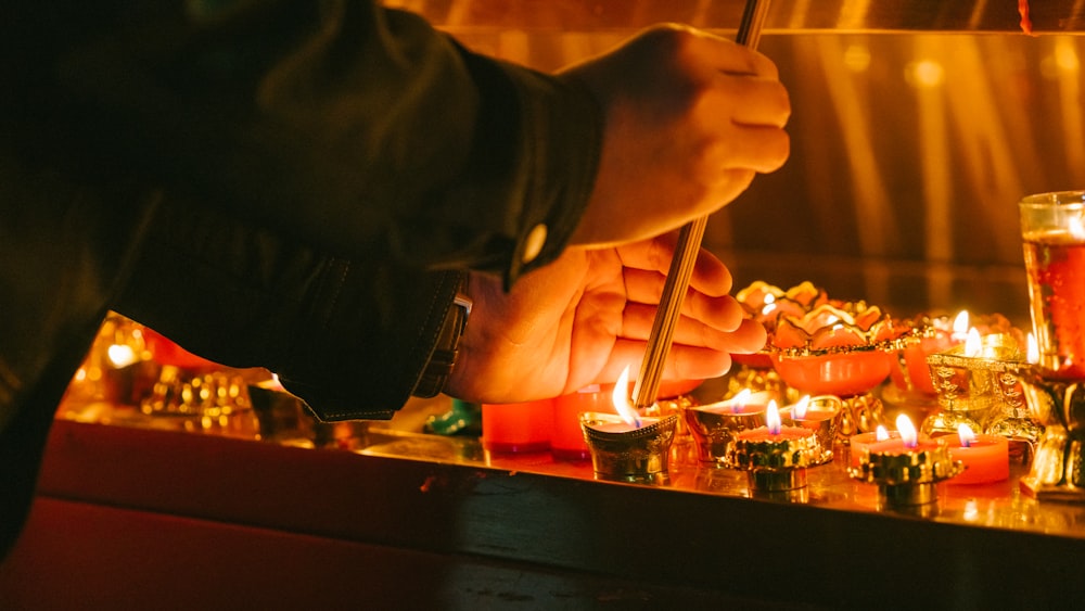 a person lighting a candle with a stick