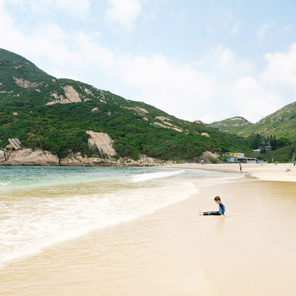 a person sitting on a beach next to the ocean