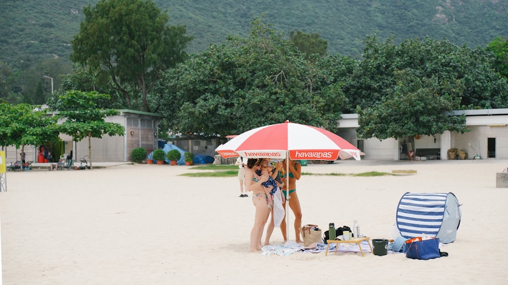 two women standing under an umbrella on a beach