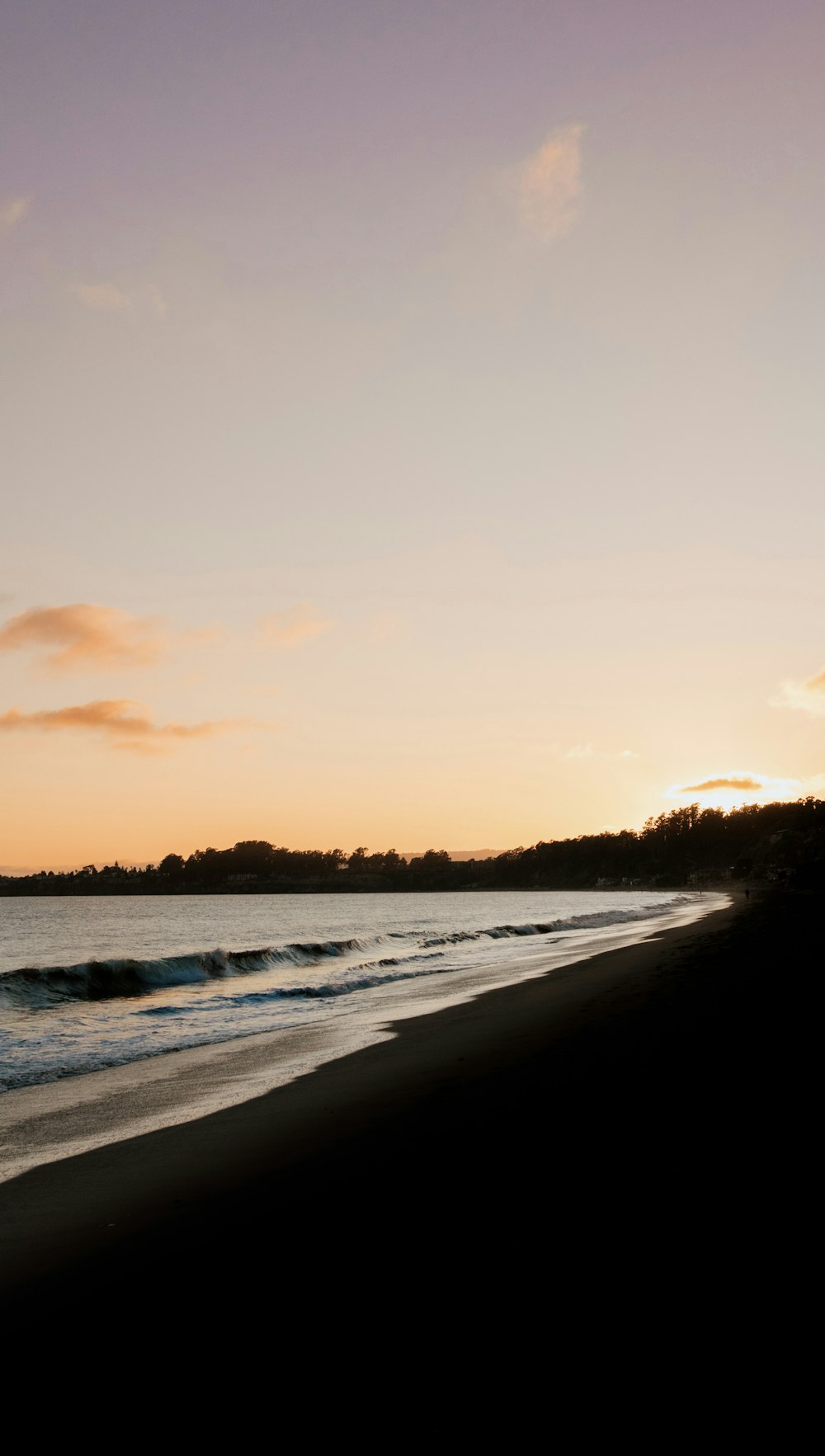 a beach with waves coming in to shore at sunset