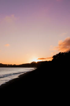 A vibrant sunset over a serene beach with gentle waves and a silhouette of a lone traveler walking along the shore.