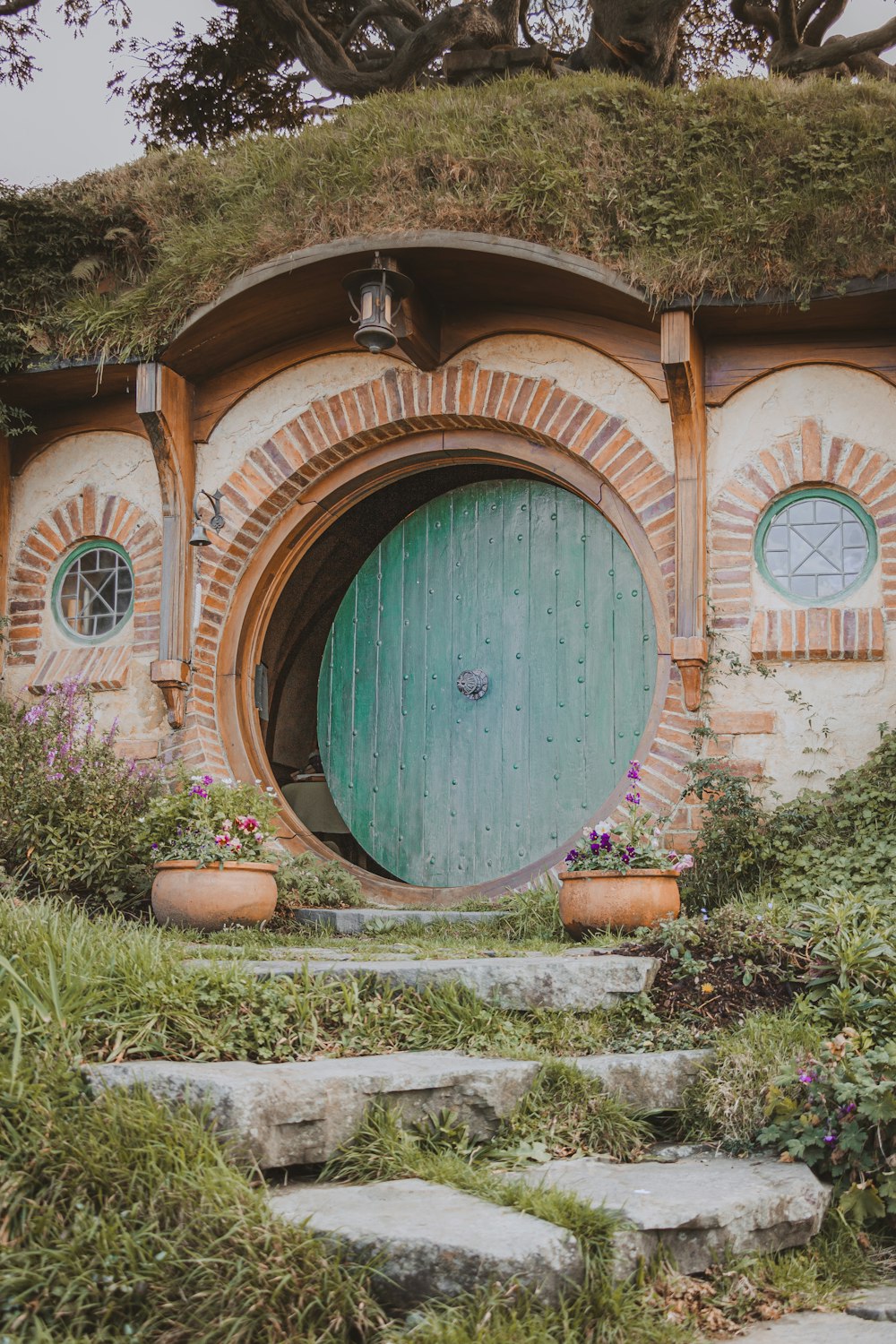 a hobbot house with a green door surrounded by greenery