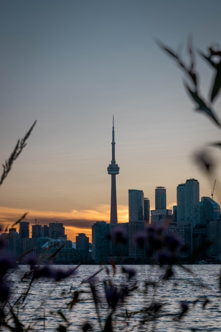 The iconic CN Tower towering over Toronto’s skyline during a glowing sunset.